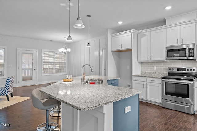 kitchen with dark wood-style floors, appliances with stainless steel finishes, white cabinets, and a sink