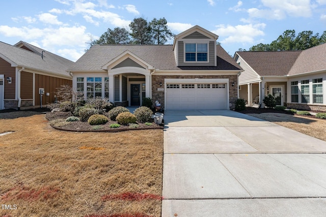 view of front facade featuring concrete driveway, stone siding, a front yard, and roof with shingles