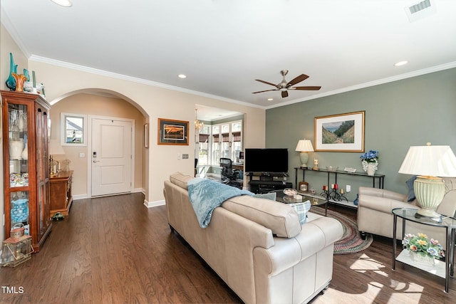 living area with visible vents, dark wood-type flooring, ornamental molding, arched walkways, and baseboards