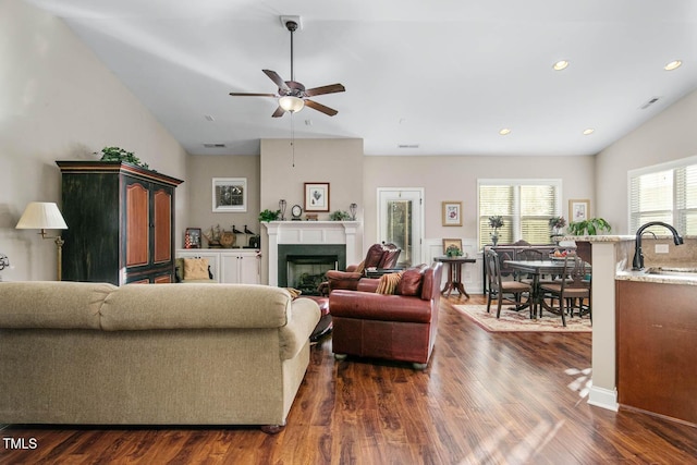 living area with a fireplace, lofted ceiling, recessed lighting, visible vents, and dark wood-type flooring