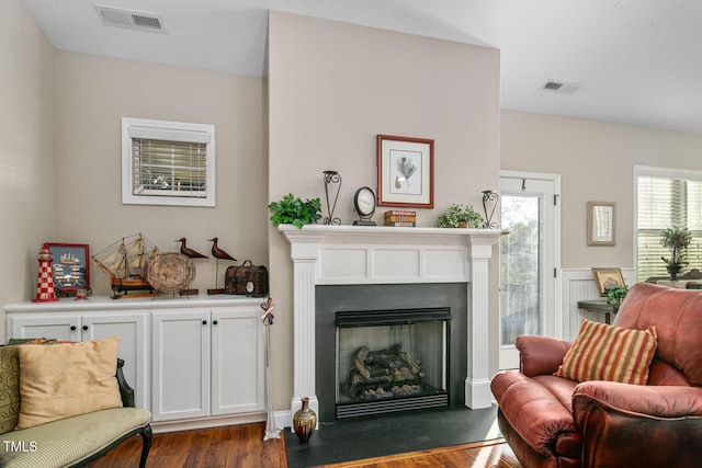 sitting room with dark wood-style floors, a fireplace with flush hearth, and visible vents