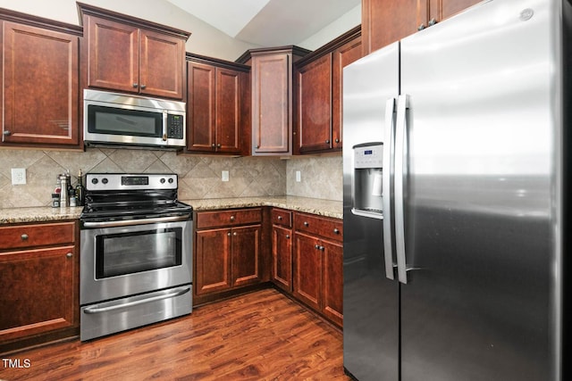 kitchen featuring stainless steel appliances, dark wood finished floors, decorative backsplash, and light stone countertops