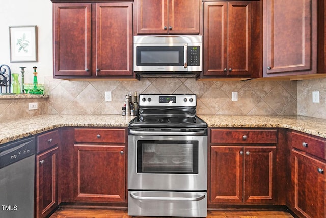 kitchen featuring reddish brown cabinets, stainless steel appliances, light stone counters, and decorative backsplash