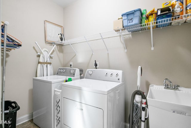 washroom with laundry area, baseboards, a sink, and washing machine and clothes dryer