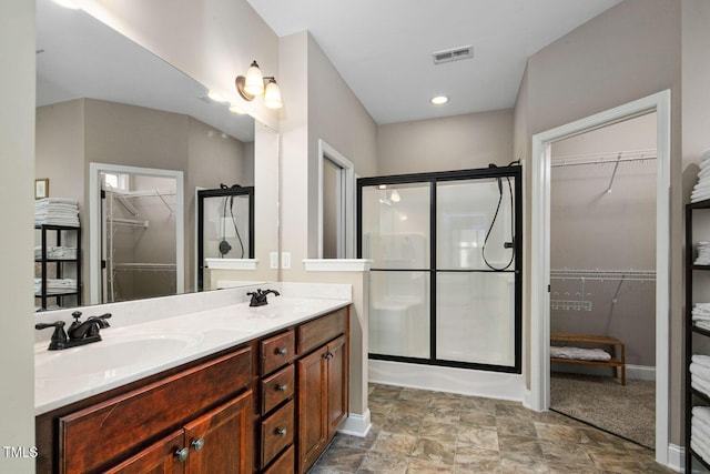 full bathroom with double vanity, a shower stall, visible vents, and a sink