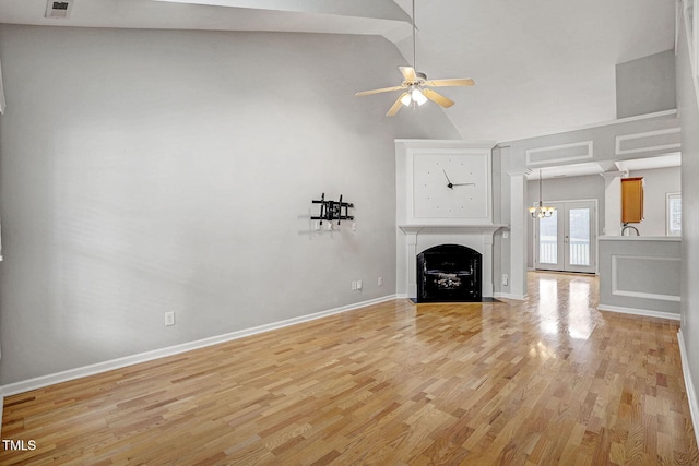 unfurnished living room with baseboards, a fireplace with flush hearth, lofted ceiling, light wood-style floors, and a ceiling fan