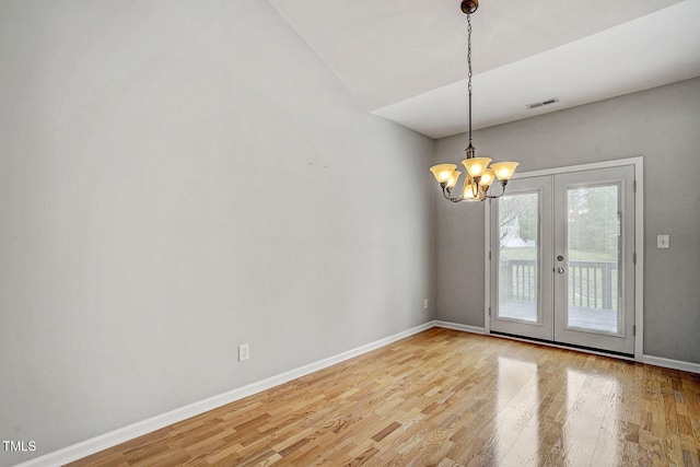 empty room with visible vents, baseboards, french doors, wood finished floors, and a notable chandelier