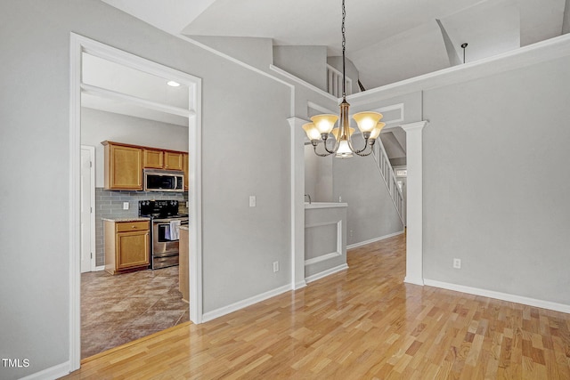 unfurnished dining area with lofted ceiling, a notable chandelier, light wood-style floors, and baseboards