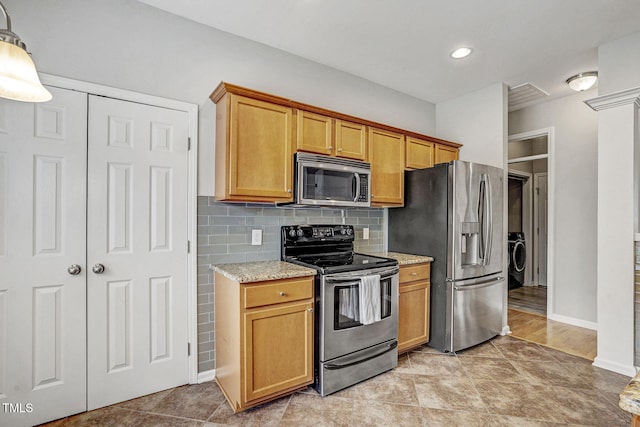 kitchen featuring baseboards, appliances with stainless steel finishes, decorative backsplash, light stone countertops, and washer / dryer