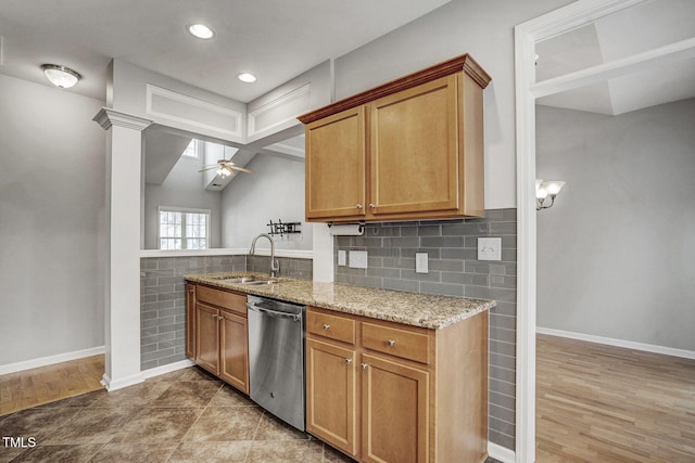 kitchen with light stone counters, ceiling fan, a sink, stainless steel dishwasher, and brown cabinets