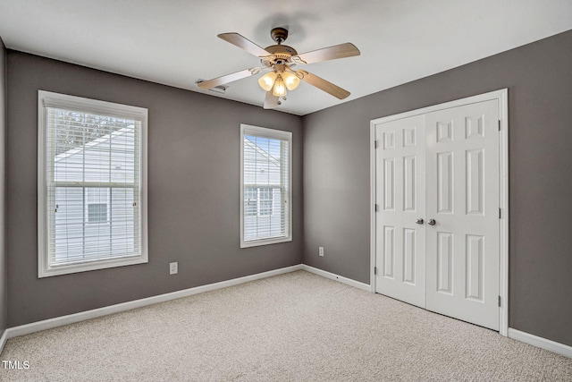 unfurnished bedroom with a ceiling fan, baseboards, a closet, and light carpet