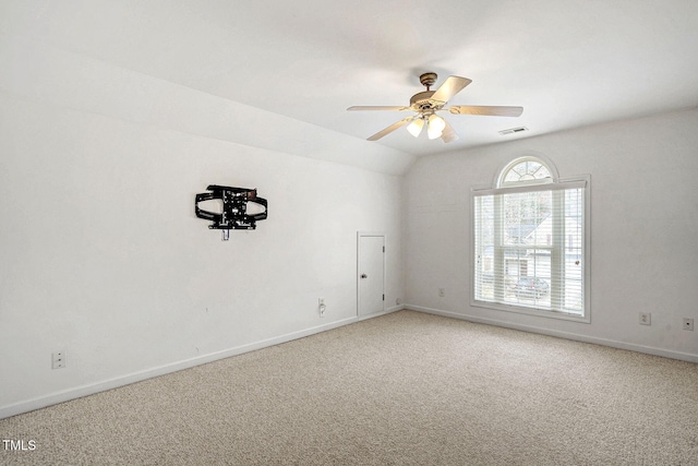 carpeted spare room with visible vents, baseboards, ceiling fan, and vaulted ceiling