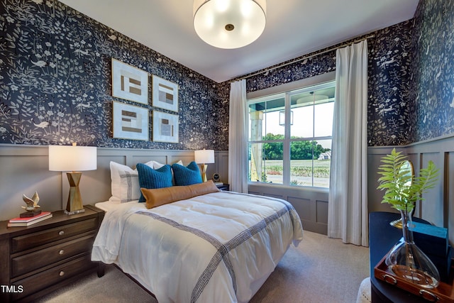 bedroom with a decorative wall, wainscoting, carpet flooring, and wallpapered walls