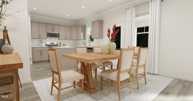 dining room featuring light wood-style floors, baseboards, crown molding, and recessed lighting