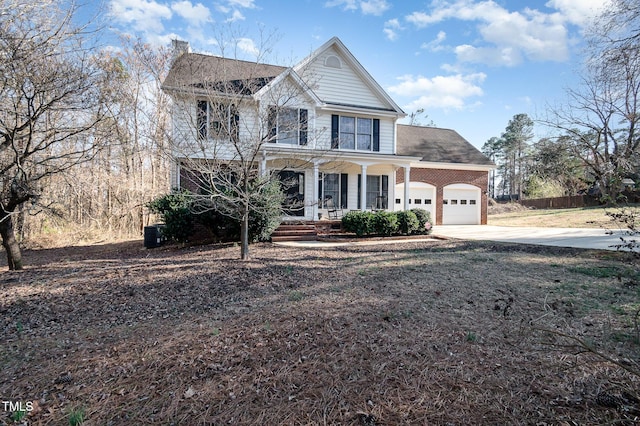 view of front of house with driveway, covered porch, an attached garage, and brick siding