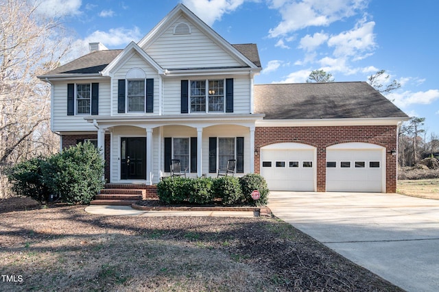 view of front facade with a porch, an attached garage, brick siding, concrete driveway, and a chimney