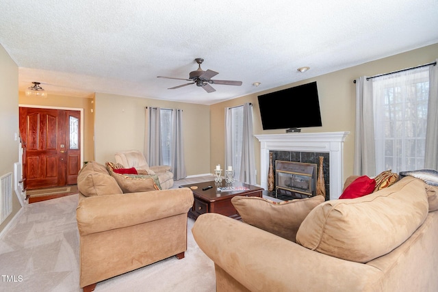 living room featuring light carpet, a textured ceiling, visible vents, and a tiled fireplace