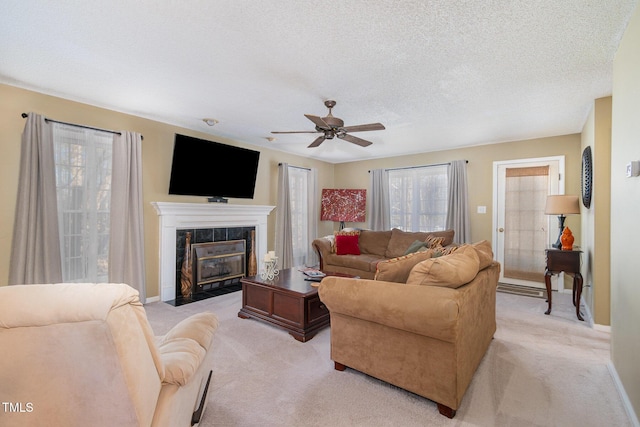 living area featuring baseboards, light carpet, a textured ceiling, and a tiled fireplace