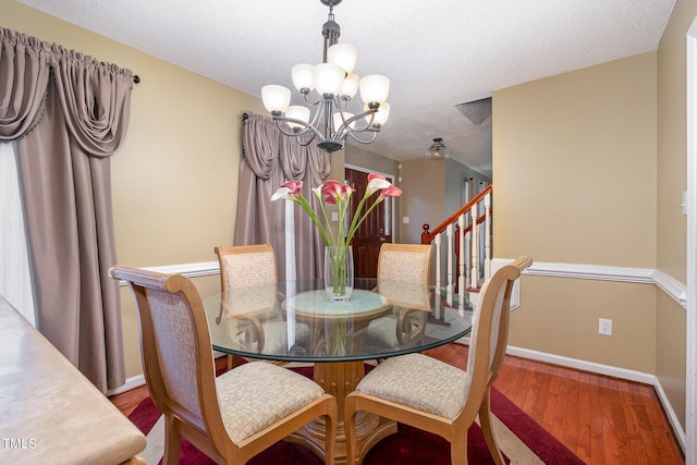 dining area featuring baseboards, a textured ceiling, a chandelier, and wood finished floors