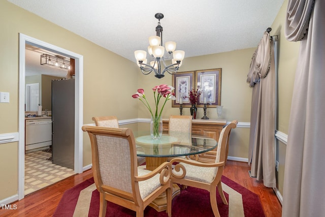 dining room featuring a notable chandelier, a textured ceiling, baseboards, and wood finished floors