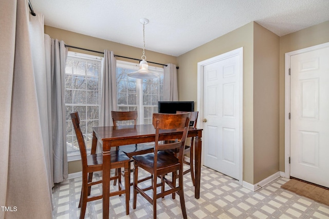 dining space featuring light floors, baseboards, and a textured ceiling