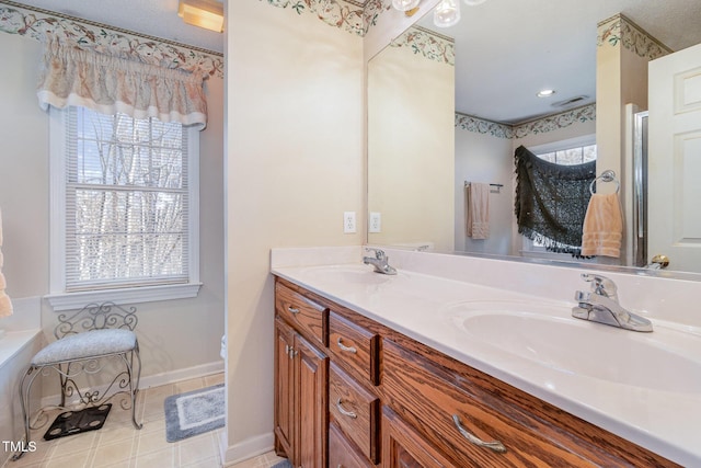 bathroom with visible vents, a sink, baseboards, and double vanity