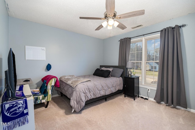 bedroom featuring ceiling fan, a textured ceiling, light carpet, visible vents, and baseboards