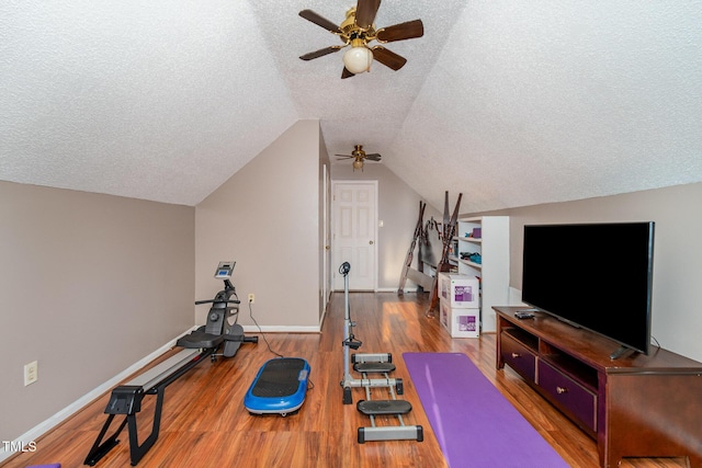 workout room with a textured ceiling, baseboards, vaulted ceiling, and wood finished floors