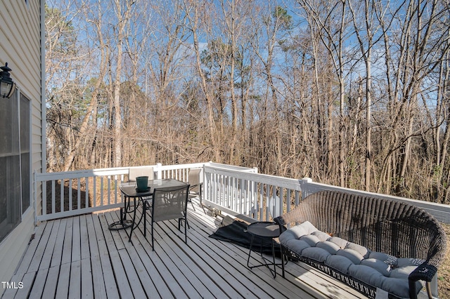 deck featuring outdoor dining space and a wooded view