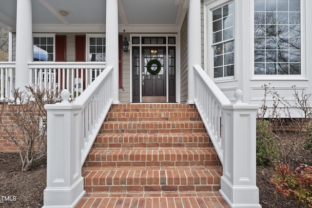 doorway to property with brick siding and covered porch