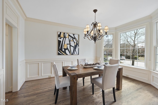 dining room with an inviting chandelier, a decorative wall, wood finished floors, and ornamental molding