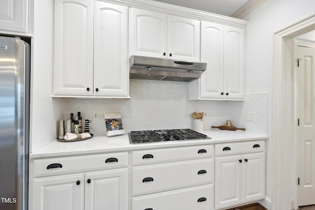 kitchen with under cabinet range hood, decorative backsplash, black gas cooktop, and freestanding refrigerator