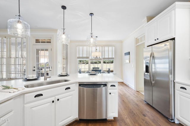 kitchen with a sink, wood finished floors, stainless steel appliances, crown molding, and light countertops