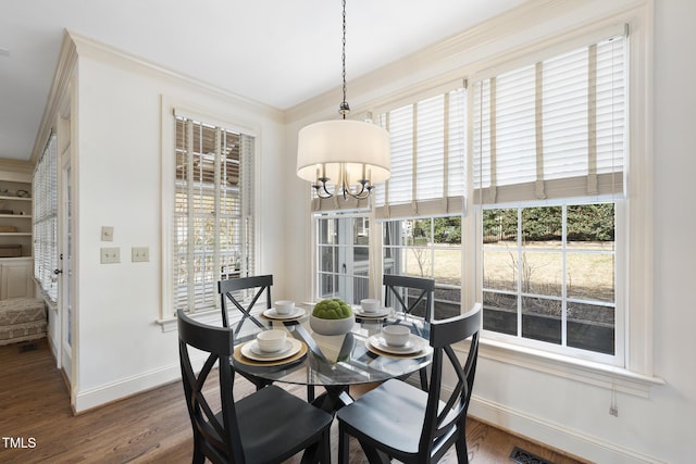 dining area with an inviting chandelier, wood finished floors, baseboards, and ornamental molding