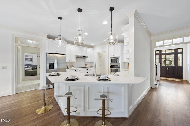 kitchen featuring wood finished floors, ornamental molding, stainless steel appliances, a sink, and white cabinetry