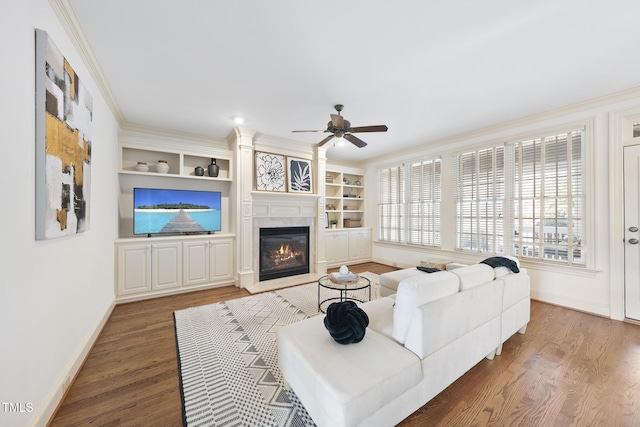 living room featuring a glass covered fireplace, wood finished floors, baseboards, and ornamental molding