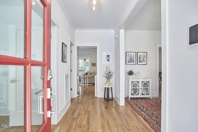 interior space with baseboards, ornamental molding, visible vents, and light wood-style floors