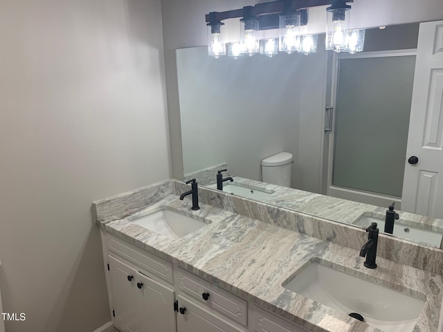bathroom with double vanity, toilet, and a sink
