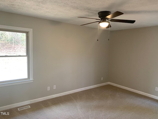 carpeted spare room featuring a textured ceiling, ceiling fan, visible vents, and baseboards