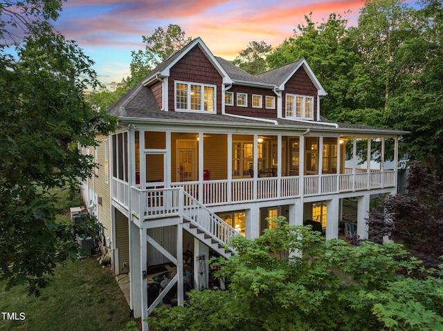 back of house at dusk featuring stairway and central AC