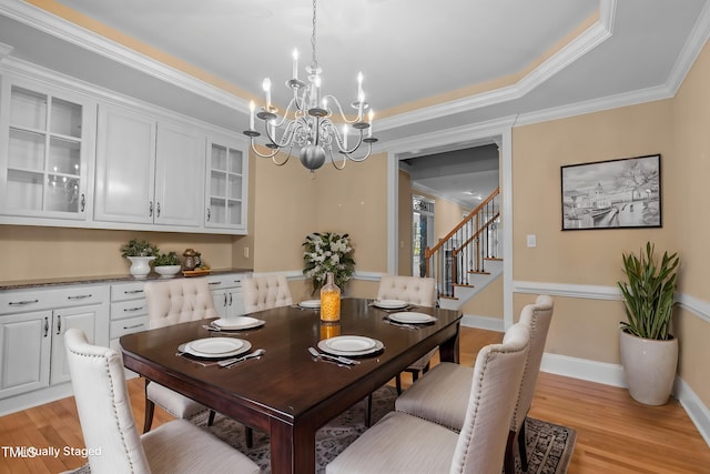 dining area with crown molding, baseboards, a chandelier, stairway, and light wood-type flooring