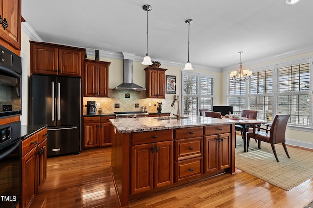 kitchen featuring a sink, high end refrigerator, crown molding, black oven, and wall chimney exhaust hood