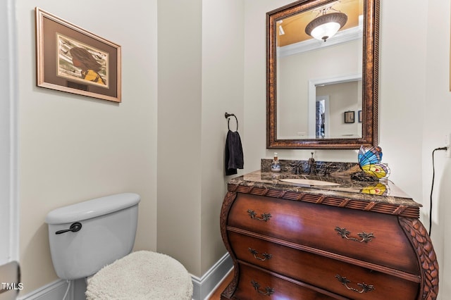 bathroom with vanity, toilet, baseboards, and ornamental molding