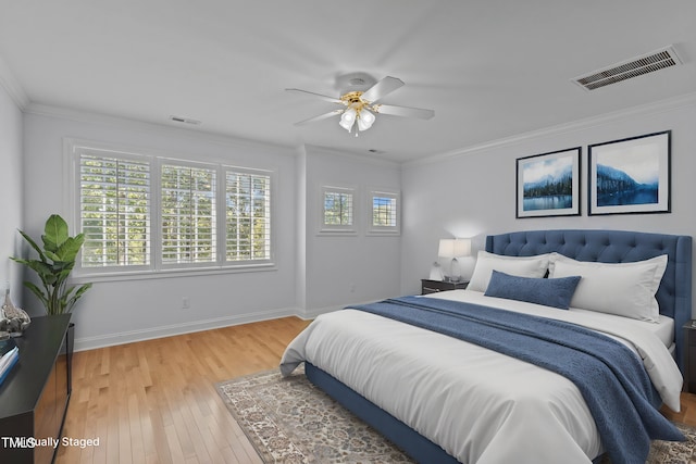 bedroom featuring visible vents, baseboards, light wood-style floors, and crown molding