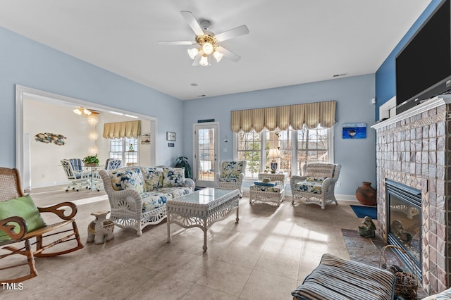 living room with baseboards, a fireplace with flush hearth, visible vents, and ceiling fan