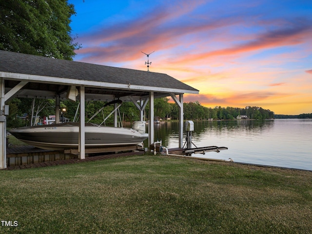 dock area with a water view, boat lift, and a lawn