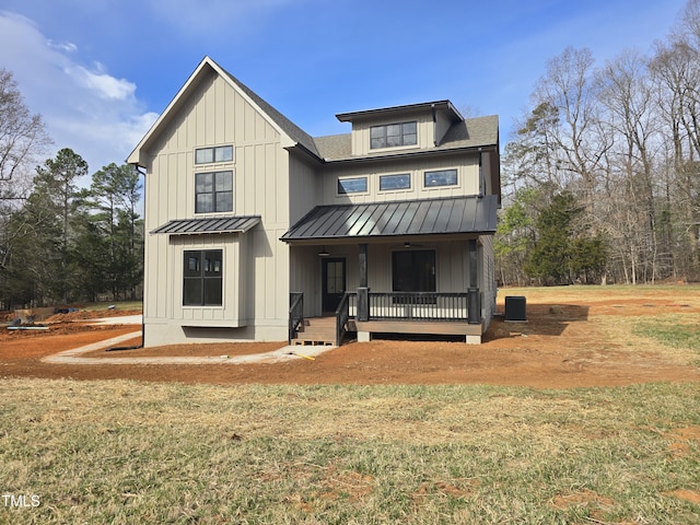 view of front of property with board and batten siding, a front yard, and a standing seam roof