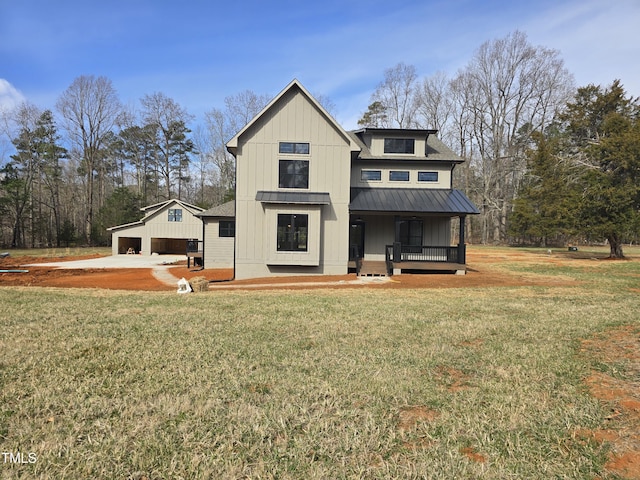 rear view of house featuring a standing seam roof, a yard, an outdoor structure, board and batten siding, and metal roof