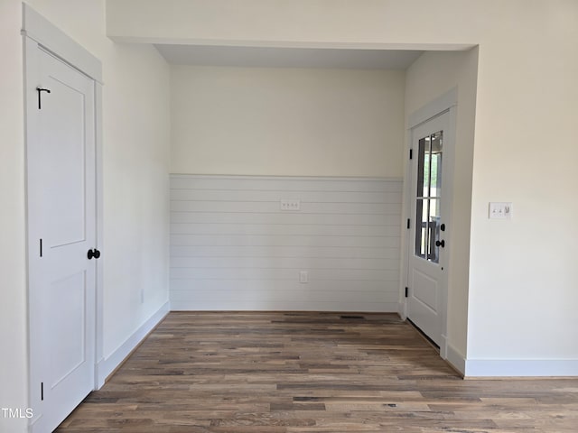 unfurnished room featuring wood finished floors, a wainscoted wall, and baseboards