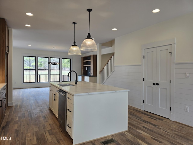 kitchen featuring light stone counters, dark wood-style flooring, visible vents, and a sink